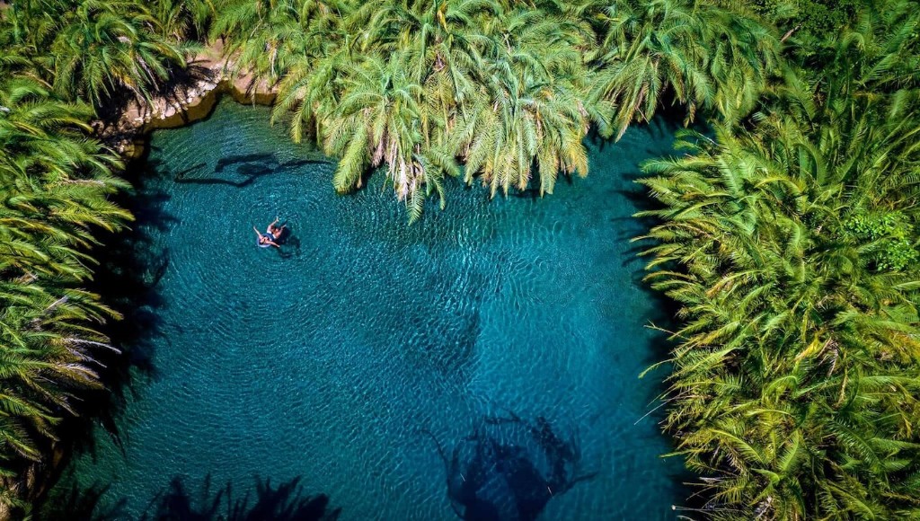 Turquoise water at Chemka Hot Spring surrounded by palms