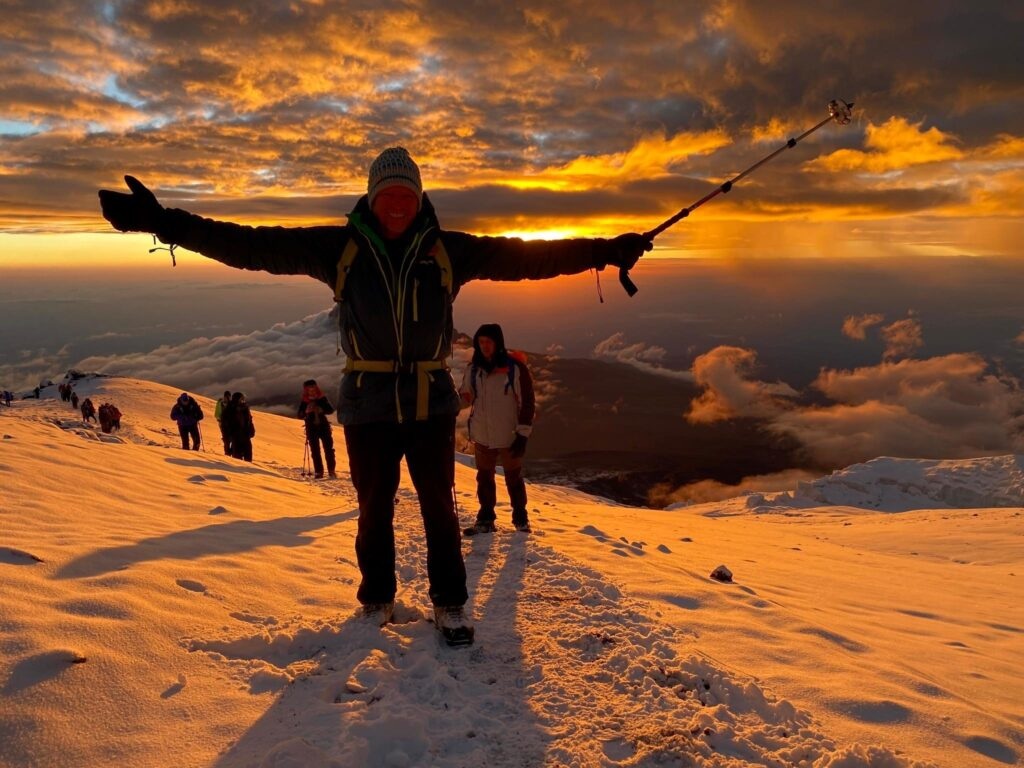 Trekkers celebrating on Mount Kilimanjaro during a golden sunrise