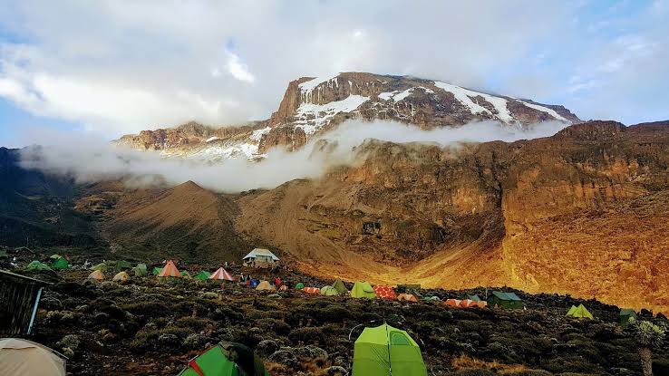 Machame Route base camp with tents beneath the summit of Kilimanjaro