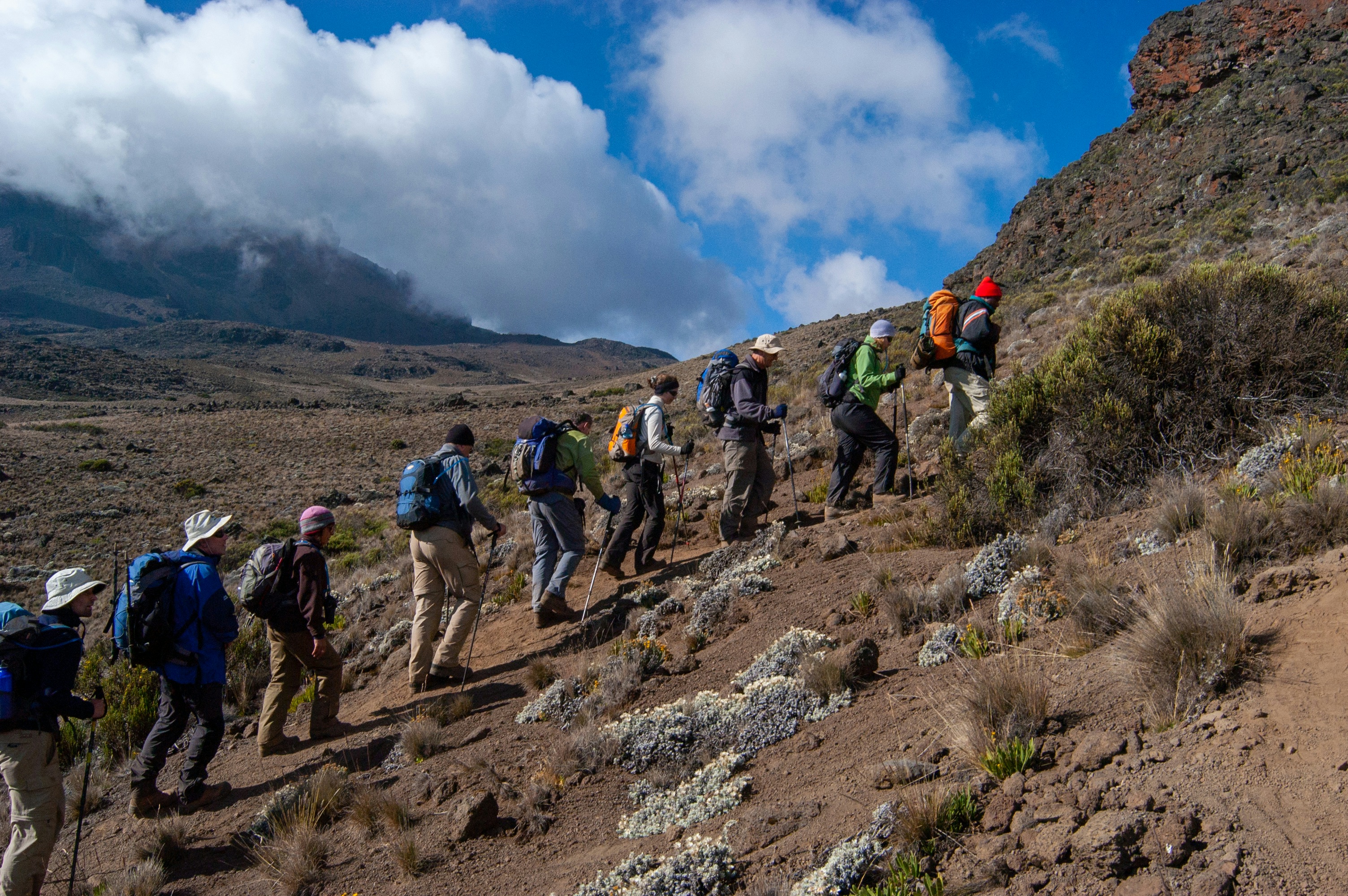 Trekkers ascending the Machame Route on Mount Kilimanjaro beneath dramatic cloud formations